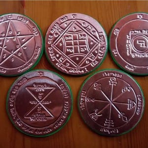 May include: Five circular copper-colored medallions with green edges, each featuring distinct embossed geometric patterns, including a pentagram, a square grid, a central square, an hourglass shape, and a radial design with various symbols.