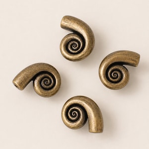 May include: Four individual metal beads, each shaped like a coiled shell or spiral. The beads feature an antique brass finish with dark, recessed areas that highlight the intricate, swirling texture of the design. Each bead has a small hole.