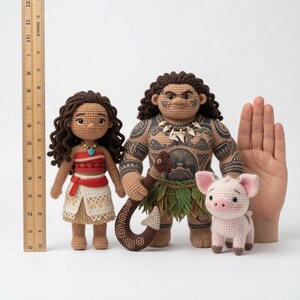 May include: Three crocheted dolls featuring a female figure with dark curly hair, a male figure with extensive dark tattoos and a hook, and a small pink pig. A wooden ruler shows the female doll is approximately 6 inches tall.