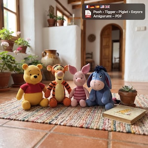 May include: Four crocheted stuffed animals including a yellow bear in a red shirt, an orange tiger with black stripes, a pink piglet, and a blue donkey. A book titled Winnie the Pooh sits next to them on a multicolored woven rug on a tiled floor.