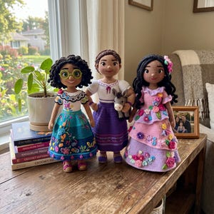 May include: Three handmade crochet dolls featuring intricate yarn details. The left doll has dark curly hair, green glasses, and a blue skirt. The center doll has brown hair and a purple skirt. The right doll has long black hair and a pink skirt.