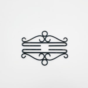 Pode incluir: Toalheiro de parede de metal preto com um design decorativo de rolagem.