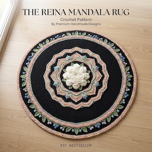 以下が含まれることがあります： Premium Handmade Designsによる「The Reina Mandala Rug」というタイトルの円形かぎ針編みラグのパターン。中央の白い花のモチーフを囲むように、黒、ソフトピンク、セージグリーン、ライトブルーの糸で編まれた同心円状のリングがあり、葉とベリーのアクセントが施されています。