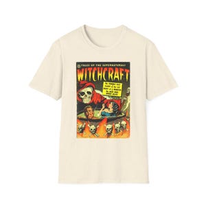 以下が含まれることがあります： Witchcraftというタイトルのヴィンテージコミックの表紙グラフィックがプリントされたクリーム色の半袖Tシャツ。赤いローブを着た骸骨、大釜の中の人物、炎に包まれた頭蓋骨が描かれており、Tales of the Supernaturalというテキストが含まれています。