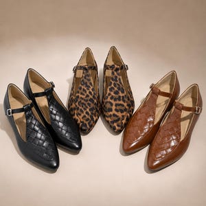 Peut inclure: Trois paires de chaussures plates à bride en T, déclinées en noir, imprimé léopard et marron. Chaque chaussure présente un bout pointu, une fine bride de cheville avec une boucle argentée et une texture matelassée tressée sur le devant.
