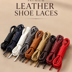 Puede incluir: Una colección de nueve cordones de cuero para zapatos enrollados en varios colores, incluyendo negro, azul marino, blanco, gris, tostado, marrón claro, marrón oscuro, granate y rojo. El texto PREMIUM LEATHER SHOE LACES aparece en la parte superior.