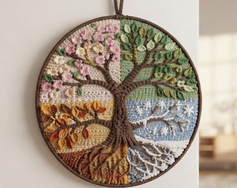 May include: A circular wall hanging featuring a crocheted tree divided into four quadrants representing the seasons. The tree has pink blossoms, green leaves, golden autumn foliage, and white snowflakes, all set within a dark brown frame.