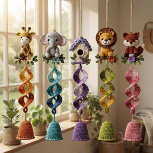 May include: Five hanging crochet ornaments featuring a giraffe, elephant, birdhouse, lion, and fox. Each animal sits on a branch with flowers, attached to a colourful spiral crochet tail and a bell-shaped base, all suspended by twine strings.