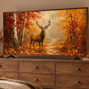 Op de afbeelding: Een groot rechthoekig televisiescherm met een gedetailleerd schilderij van een majestueus hert in een herfstbos. De scène toont levendig oranje en geel gebladerte, berkenbomen en een hert met een groot gewei in het midden van het beeld.