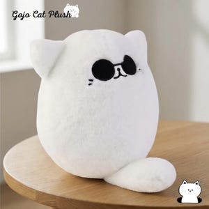May include: A white plush cat toy with a rounded body, pointed ears, and a small tail. The cat features embroidered black sunglasses, a simple nose, and whiskers. The text Gojo Cat Plush is visible in the upper left corner of the image.