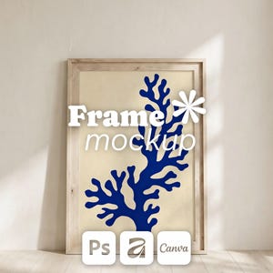 May include: A light wood frame containing a cream-colored print with a dark blue organic coral-like shape. The text "Frame mockup" is overlaid in white, accompanied by a white flower icon and three small square logos labeled Ps, a, and Canva.