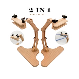 Puede incluir: Un soporte de bordado de madera 2 IN 1 NEW 190-24 con un brazo articulado ajustable con perillas negras y una base ancha. Dos recuadros circulares muestran el soporte sosteniendo diferentes bastidores, uno blanco y uno azul claro.