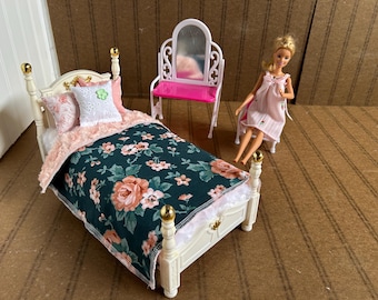 Könnte beinhalten: Ein Puppen-Schlafzimmer-Set mit einem weißen Bett, einem rosa Schminktisch und einer Puppe. Das Bett hat eine Bettdecke mit Blumenmuster und Kissen. Der Schminktisch ist weiß mit einer rosa Tischplatte und einem Spiegel. Die Puppe trägt ein rosa Kleid.
