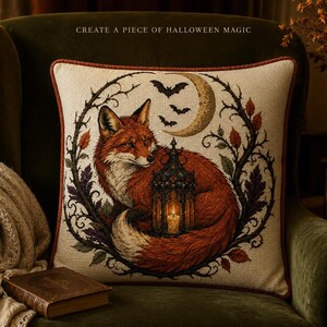 Peut inclure: Un coussin carré avec une illustration imprimée d'un renard roux enroulé autour d'une lanterne allumée. Le motif comprend un croissant de lune, des chauves-souris et une bordure de vignes épineuses. Le texte CREATE A PIECE OF HALLOWEEN MAGIC est inscrit.