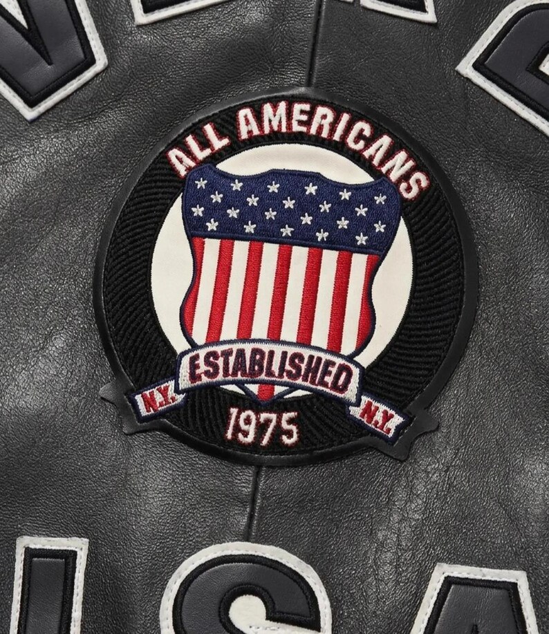 May include: A black leather jacket featuring a circular embroidered patch with the text ALL AMERICANS, ESTABLISHED, and 1975. The patch displays a shield with a blue field of white stars and red and white vertical stripes, flanked by N.Y. text.