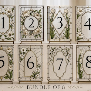 Peut inclure: Un ensemble de huit panneaux de table rectangulaires avec des cadres de style vitrail, des illustrations florales et des chiffres noirs de un à huit. Chaque panneau est sur un petit support métallique avec le texte BUNDLE OF 8 en dessous.