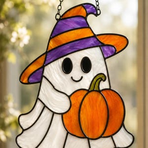 Könnte beinhalten: Ein Buntglas-Suncatcher in Form eines Geistes, der einen lila-orange gestreiften Hexenhut trägt. Die weiße Geisterfigur hält einen leuchtend orangefarbenen Kürbis mit grünem Stiel. Das gesamte Stück ist schwarz umrandet und hängt an einer Kette.