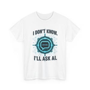 Op de afbeelding: Een wit t-shirt met korte mouwen en een centrale afbeelding van een gloeiend blauw, cirkelvormig printplaatpatroon met een tekstballon-icoon in het midden. De tekst I DON'T KNOW. I'LL ASK AI. staat in donkergrijs boven en onder de afbeelding.