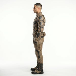 May include: A tan and black tactical jumpsuit featuring reinforced padding on the shoulders, elbows, and knees. The garment includes integrated gloves, a utility belt with pouches, and matching tan and black tactical boots, shown from a side profile.