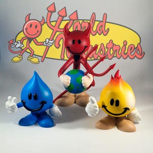 May include: Three World Industries character figurines. A central red devil figure holds a globe and a trident. To the left, a blue water drop character makes a peace sign. To the right, a yellow flame character gives a thumbs up. All have smiley faces.