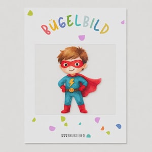 Puede incluir: Una tarjeta blanca con el texto BÜGELBILD y WWW.BURGFROLLEIN.DE junto a formas de confeti de colores. En el centro hay una ilustración en acuarela de un superhéroe con cabello castaño, máscara roja, traje azul con un rayo amarillo y capa roja.