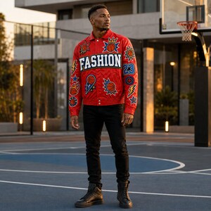 Peut inclure: Une veste rouge vif arborant le mot FASHION en grandes lettres blanches sur la poitrine, ornée de divers écussons colorés incluant des ballons de basket, des éclairs, des étoiles et le nombre 23, portée avec un pantalon et des baskets noirs.