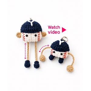 May include: Two crochet baseball characters with navy blue caps and white bodies featuring red stitching. One character has long dangling tan legs with navy blue feet, while the other has bent arms and legs. Text reads Watch video.