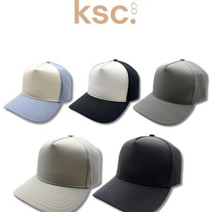 May include: Five baseball caps with perforated side panels and solid front panels, arranged in two rows. The top row features a light blue and white cap, a black and white cap, and a solid grey cap. The bottom row includes a light grey cap and a solid black cap. The text kenz supply co ksc is at the top.