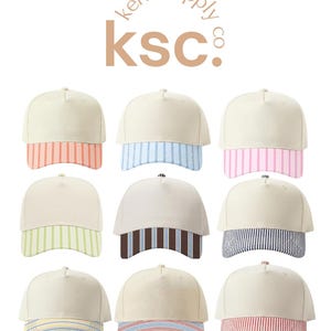 May include: Nine baseball caps arranged in a grid, each featuring a solid cream crown and a unique striped brim. The text kenz supply co. ksc. appears at the top. The brims display various color combinations including orange, blue, pink, green, brown, navy, yellow, and red stripes.