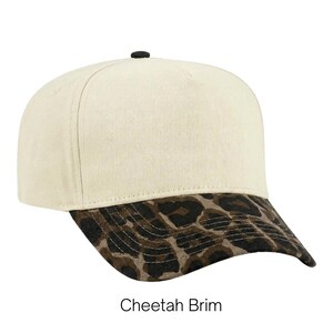 May include: A baseball cap with a cream-colored crown and a black button on top. The brim features a brown and black cheetah print pattern. The text "Cheetah Brim" is printed in black below the cap against a plain white background.