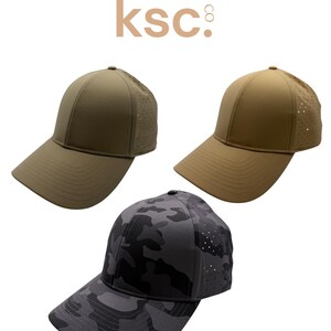 May include: Three baseball caps with the text kenz supply co. ksc. One cap is olive green, one is tan, and one features a dark gray camouflage pattern. Each cap has a solid front panel and a perforated back panel for ventilation.