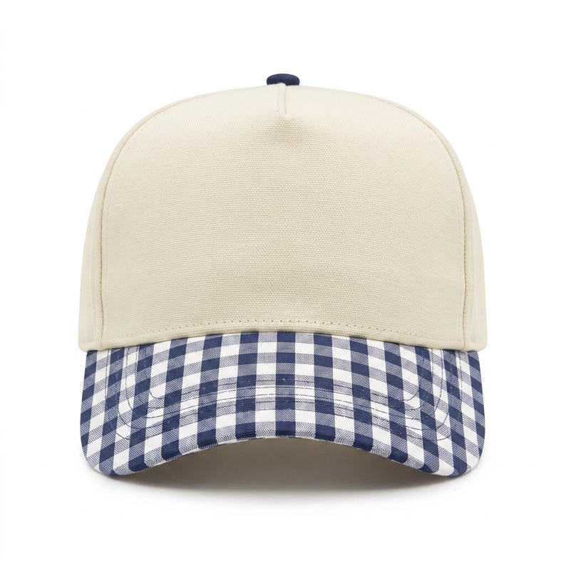 May include: A five-panel baseball cap featuring a solid cream-colored crown and a navy blue and white gingham checkered brim. The cap includes a small navy blue button at the top center, structured front panels, and a curved visor design.