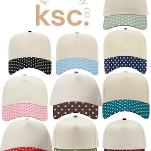 May include: A collection of eleven baseball caps featuring a cream-colored crown and a curved brim with a white polka dot pattern in various colors including sage, black, light blue, navy, pink, brown, teal, red, olive, and maroon. The text kenz supply co ksc is visible.