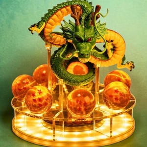 May include: A green dragon figurine with brown horns and red eyes, coiled above seven translucent orange spheres, each containing a varying number of red stars. The entire display is mounted on a circular, illuminated clear acrylic stand.