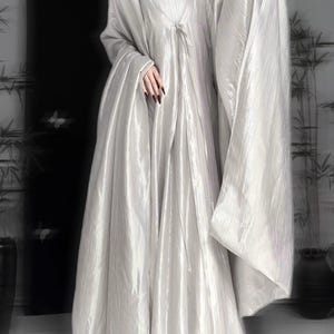 K&ouml;nnte beinhalten: Ein bodenlanges, schimmerndes silbernes Kleid mit quadratischem Ausschnitt, plissiertem Oberteil und langen, weiten, flie&szlig;enden &Auml;rmeln. Das Kleidungsst&uuml;ck besteht aus einem leichten, reflektierenden Stoff, der bis zum Boden f&auml;llt und eine volumin&ouml;se Silhouette erzeugt.