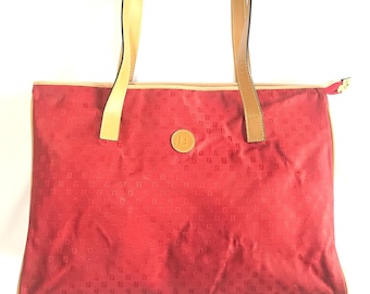 May include: Red tote bag with a brown leather handle and a small logo on the front. The bag is made of a fabric with a repeating pattern of small squares.