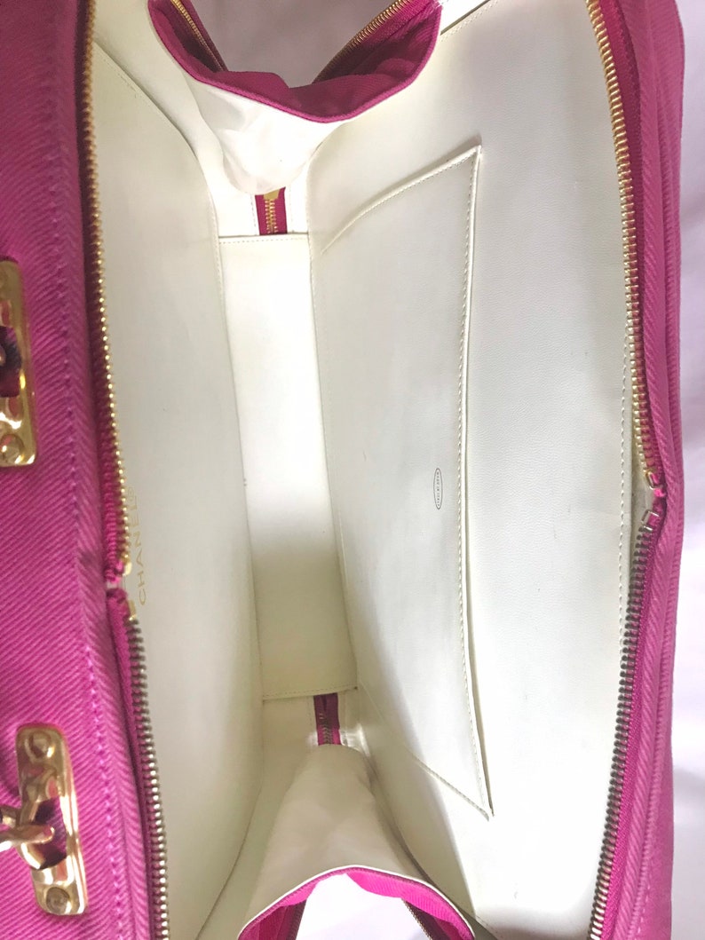 May include: The inside of a pink fabric handbag with a white lining and a zipper closure. The bag has a small pocket on the inside.