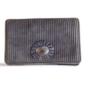 May include: A black clutch purse with a silver oval-shaped buckle and a pleated design.