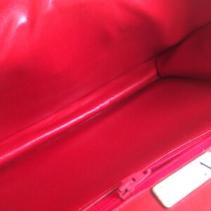 May include: The inside of a red handbag with a zipper and a white tag with the number "1" on it.