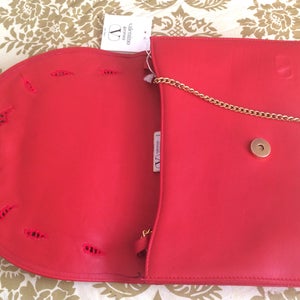 May include: Red leather clutch purse with a gold chain strap and a Valentino Garavani logo tag. The purse has a flap closure and a decorative cut-out design.