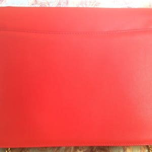 May include: A bright red leather clutch bag with a gold chain strap.