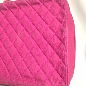 May include: A pink quilted handbag with a gold chain strap. The bag has a diamond-shaped quilted pattern.