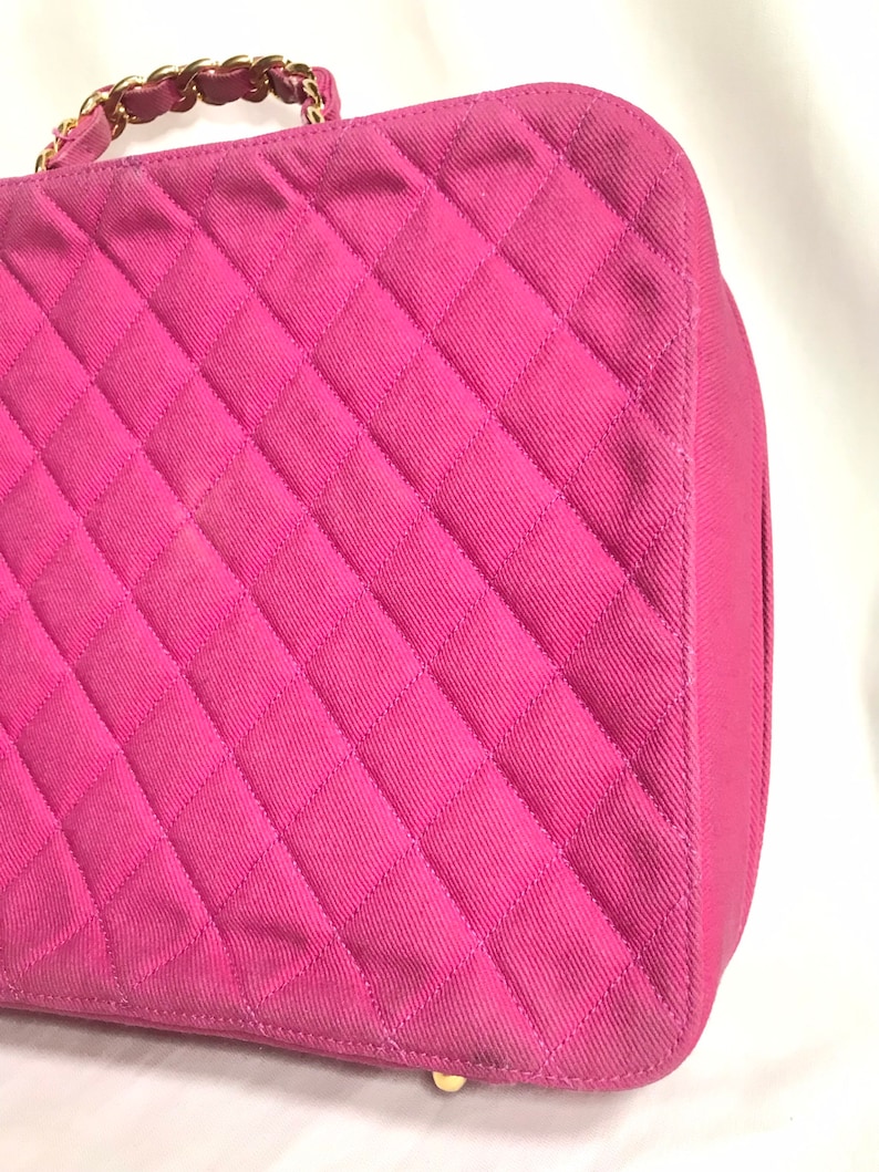 May include: A pink quilted handbag with a gold chain strap. The bag has a diamond-shaped quilted pattern.