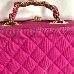 May include: A pink quilted handbag with a gold chain strap. The bag has a diamond-shaped quilted pattern.