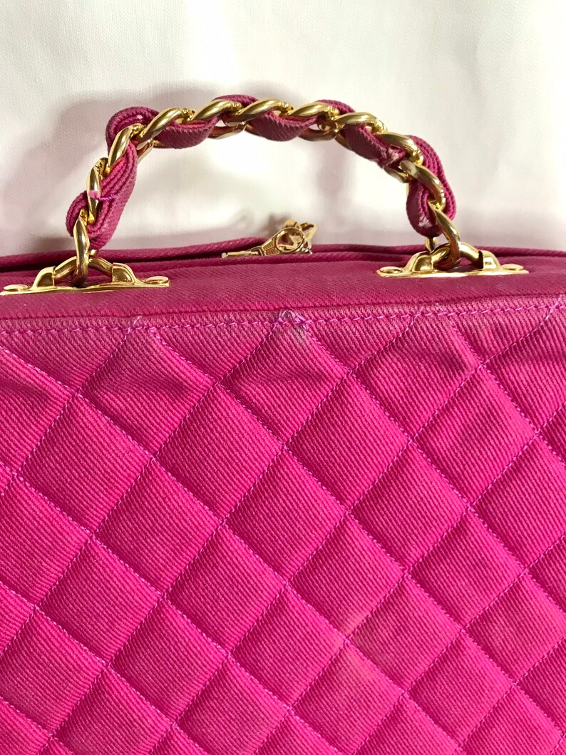 May include: A pink quilted handbag with a gold chain strap. The bag has a diamond-shaped quilted pattern.