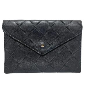 May include: A black leather wallet featuring a quilted diamond pattern across the surface. The wallet has an envelope-style flap closure secured with a small gold-toned interlocking CC logo emblem centred on the front point of the flap.