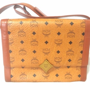 Vintage MCM brown monogram shoulder bag with leather straps and golden star shape logo motif closure. Designed by Michael Cromer. 060621r1
