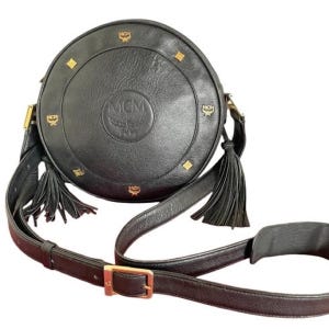 Vintage MCM black suzy wong, grained leather round shoulder bag with golden logo studs and fringes. Designed by Michael Cromer. 0407051