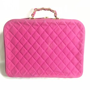 May include: A pink quilted handbag with a gold chain handle.