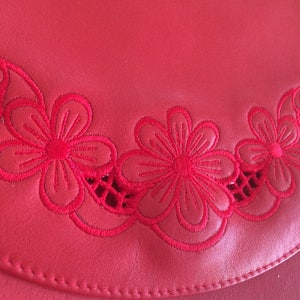 May include: Red leather purse with a decorative embroidered border of red flowers.